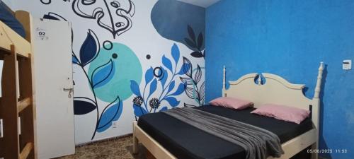 a bedroom with a bed with a blue wall at Hostel Casarão do Surf in Bertioga