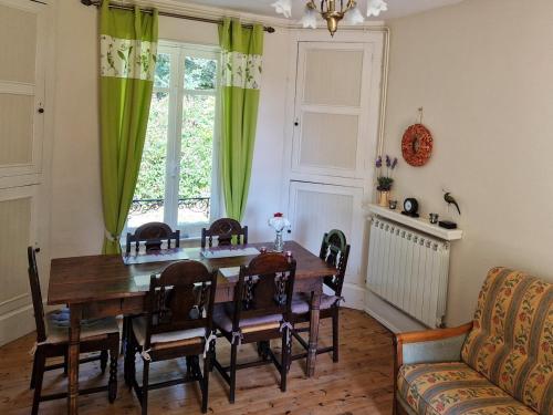 une salle à manger avec une table en bois et des rideaux verts dans l'établissement Romantic 19th century house with large garden and BBQ, à La Celle-sous-Gouzon