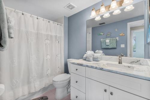 Un baño con inodoro, lavabo y espejo. en Fun and Magical Beach Escape - Amazing Beach Condo - Roelens, en Fort Myers Beach
