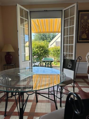 - une table et des chaises en verre dans le salon dans l'établissement Villa Les Volets Verts, à Blainville-sur-Mer