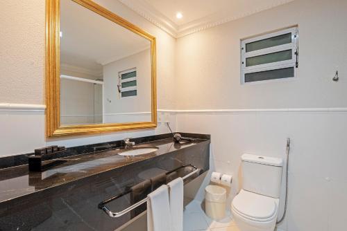 a bathroom with a sink and a toilet and a mirror at Rockefeller by Slaviero Hotéis in Curitiba