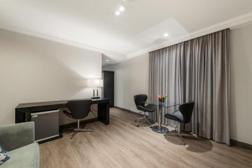 a living room with a desk and chairs at Rockefeller by Slaviero Hotéis in Curitiba