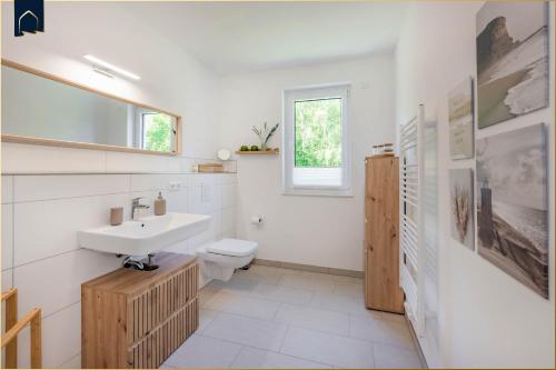 a white bathroom with a sink and a toilet at Ferienwohnung Peppi in Loddin