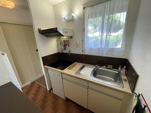 une petite cuisine avec un évier et une fenêtre dans l'établissement T3 calme avec terrasse, clim et parking proche plage - FR-1-106-45, à Saint-Cyprien