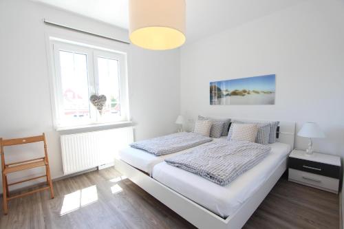a white bedroom with a bed and a window at Ferienhaus Stefanie 1 in Langeoog