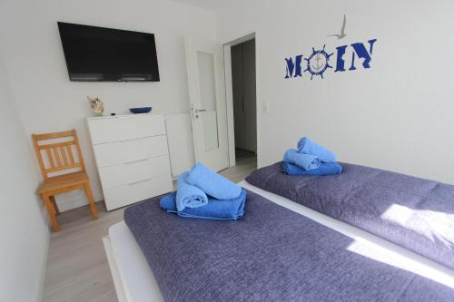 two beds with blue pillows in a room at Lüttje Parl in Langeoog