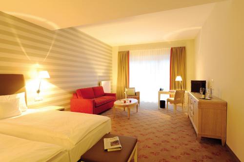 a hotel room with a bed and a red chair at Landhotel Sanct Peter in Bad Neuenahr-Ahrweiler
