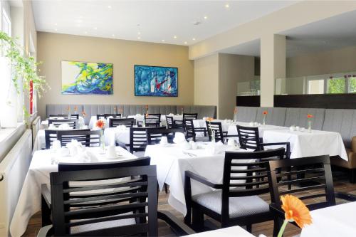 a dining room with white tables and chairs at Landhotel Sanct Peter in Bad Neuenahr-Ahrweiler