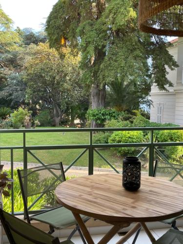 une table en bois avec deux chaises et une tasse à café sur un porche dans l'établissement Villa Francia 2P with splendid pool -private rental, à Cannes