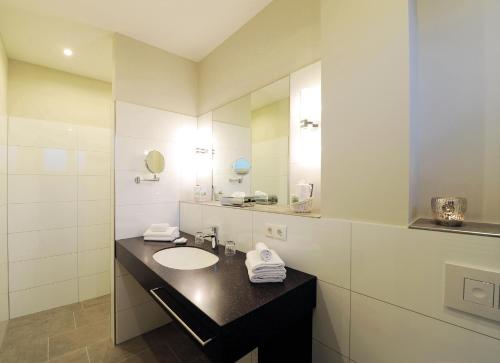 La salle de bains est pourvue d'un lavabo et d'un miroir. dans l'établissement Landhotel Sanct Peter, à Bad Neuenahr-Ahrweiler
