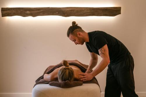 a man standing next to a woman laying on a bed at Combe Grove Health and Wellness in Bath