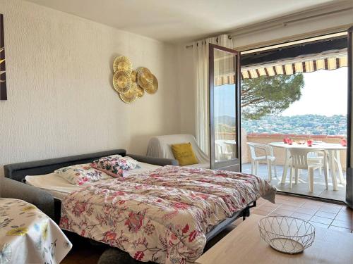 a bedroom with a bed and a balcony with a table at Bormes-les-Mimosas: Appt climatisé, 5 couchages, parking, grande terrasse - FR-1-251-136 in Bormes-les-Mimosas