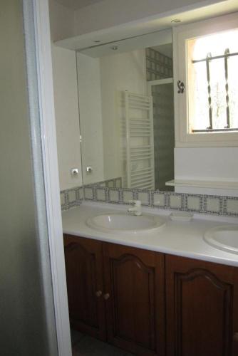 une salle de bain avec deux lavabos et un grand miroir dans l'établissement Gite de veronique & alain, à Salernes