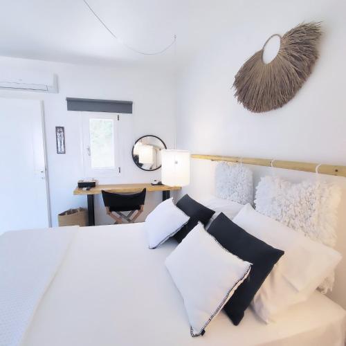 a bedroom with a white bed with black and white pillows at Island Magic - Seaview Villa with Jacuzzi Pool in Ambelas