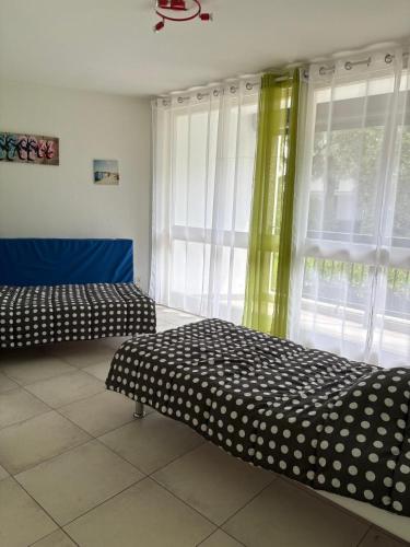 deux lits assis dans une pièce avec une fenêtre dans l'établissement Grand appartement familial a 2 pas du port de St Cyprien, à Saint Cyprien Plage