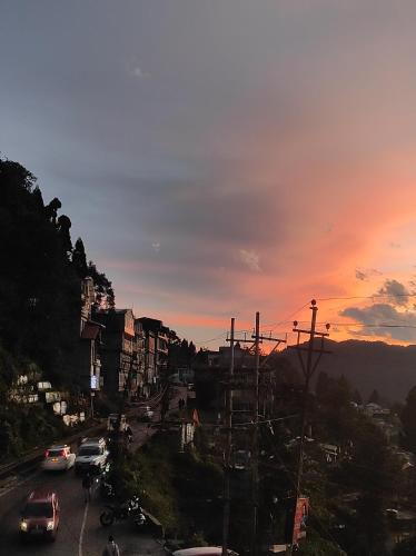 a city with cars parked on a street at sunset at HoneyBell Homestay in Darjeeling
