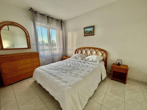 une chambre avec un lit, une commode et un miroir dans l'établissement T2 Climatisé Proche Plage avec Terrasse et Garage - FR-1-816-14, au Lavandou