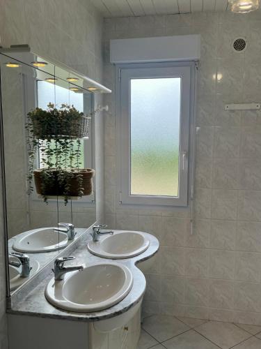 une salle de bain avec deux lavabos et une fenêtre dans l'établissement Gîtes de la Mouette L'Estran 8 à 9 personnes, à Ravenoville