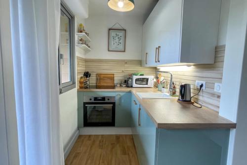 une petite cuisine avec un évier et un micro-ondes dans l'établissement T2 apartment with balcony near beach, à Houlgate