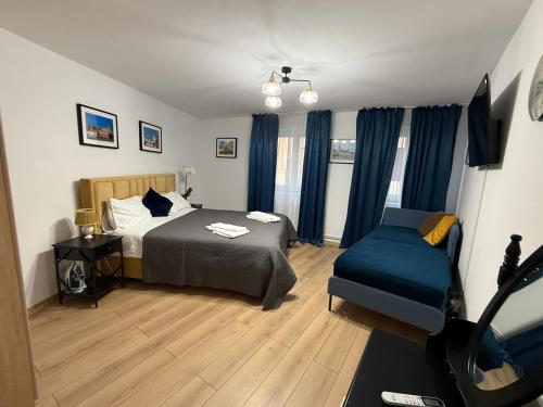 a bedroom with a bed and a couch and blue curtains at Sweet-Bombon Sibiu in Sibiu