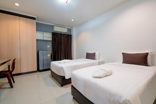a hotel room with two beds and a desk at JT Place Buriram in Buriram