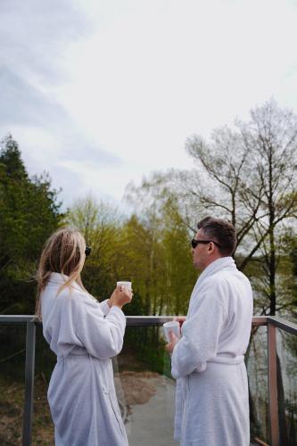 a man and a woman standing on a bridge drinking coffee at Blue&Green Masurian Hotel in Węgorzewo