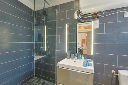 La salle de bains est pourvue de carrelage bleu, d'un lavabo et d'un miroir. dans l'établissement Appartement Cosy, à Toulon
