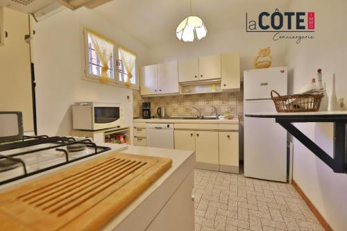 La cuisine est équipée d'appareils électroménagers blancs et d'un four avec plaques de cuisson. dans l'établissement Chez Ginou, à Sausset-les-Pins