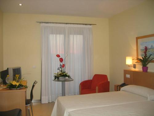 ブージャスにあるHotel SGのベッドルーム1室(ベッド1台、椅子、窓付)