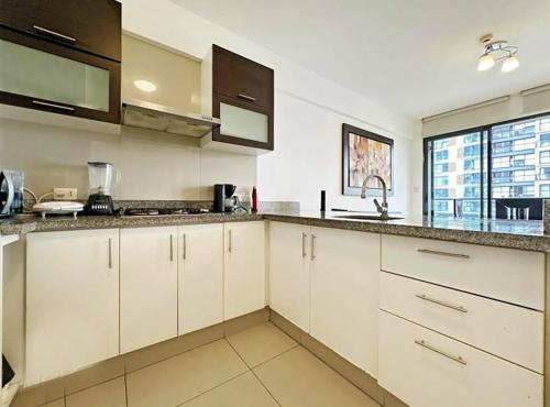a kitchen with white cabinets and a large window at Apartamento dúplex exclusivo y céntrico in Lima