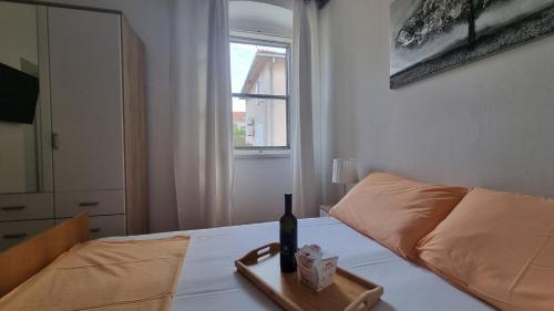 a bottle of wine on a tray on a bed at Ivory Apartment in Biograd na Moru