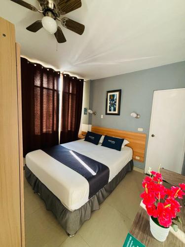 a bedroom with a bed with a ceiling fan and flowers at Ayenda Apart La Hacienda in Piura