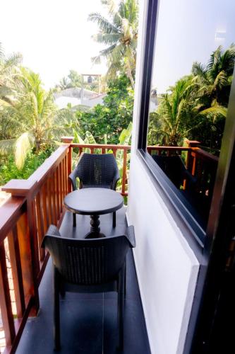 a table and chairs on a balcony with a window at Lucky Monkey Inn and Restaurant in Weligama