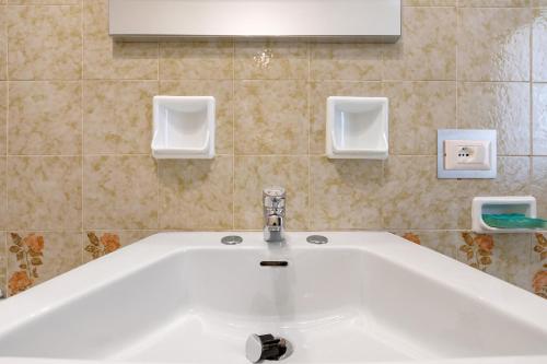 a white sink in a bathroom with two soap dispensers at Appartamenti Panelatti in Bono