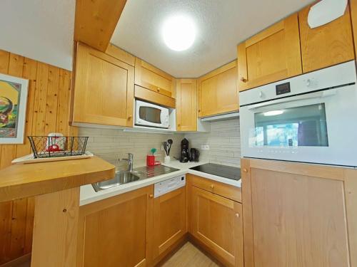 - une cuisine avec des placards en bois et des appareils blancs dans l'établissement Appartement ensoleillé 3 pièces - 6 pers avec cheminée au Grand Bornand, proche des pistes - FR-1-241-117, au Grand-Bornand