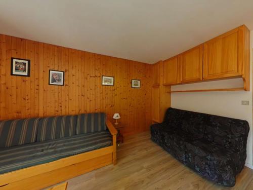 - un salon avec un canapé et des murs en bois dans l'établissement Studio fonctionnel 4 pers avec balcon sud, parking, animaux admis - FR-1-241-65, au Grand-Bornand