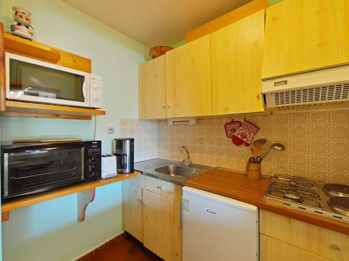 une petite cuisine avec un micro-ondes et un évier dans l'établissement Studio fonctionnel 4 pers avec balcon sud, parking, animaux admis - FR-1-241-65, au Grand-Bornand