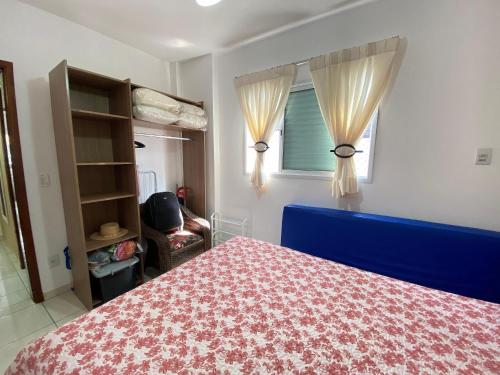 ein Schlafzimmer mit einem blauen Bett und einem Fenster in der Unterkunft Conforto na Praia – Apto 2 Qtos Guilhermina in Praia Grande