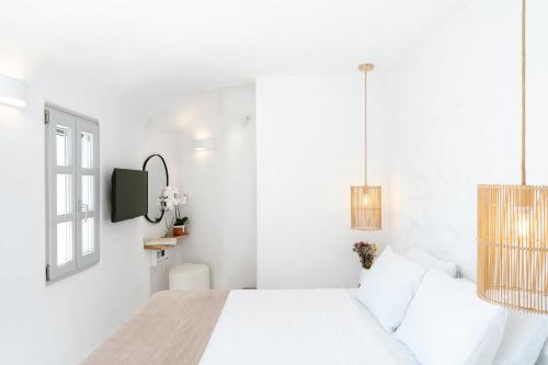 a white bedroom with a bed and a tv at Nano Oia Canaves in Oia