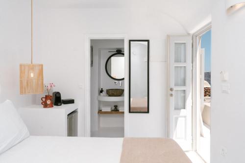 a white bedroom with a mirror and a bed at Nano Oia Canaves in Oia