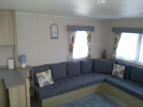 a living room with a blue couch and two windows at Kingfisher New Horizon Firs 8 Berth Blow Heated in Ingoldmells
