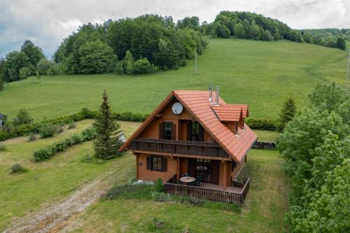 a house with a red roof on a green field at Rustikalna kuća Snowdrop s kaminom u Begovom Razdolju, Gorski kotar in Begovo Razdolje