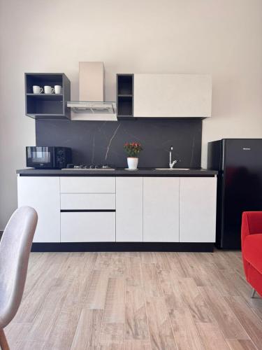 a kitchen with white cabinets and a red chair at Galaxy Rooms Tropea in Drapia