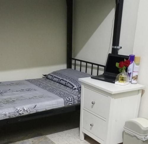 une chambre avec un lit avec un ordinateur portable sur une commode dans l'établissement ABD Cottages, à Abu Dhabi