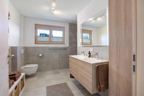 a bathroom with a sink and a toilet and a mirror at Ferienwohnung Alpenliebe in Höchenschwand