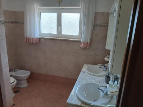 a bathroom with two sinks and a toilet at La casa di ale in Latina