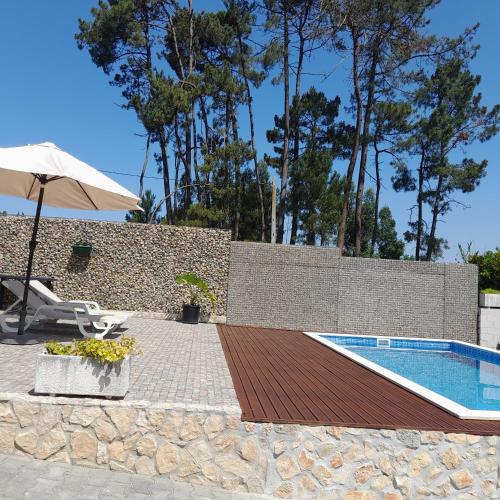 a swimming pool with an umbrella next to a brick wall at leiria village casa village in Leiria