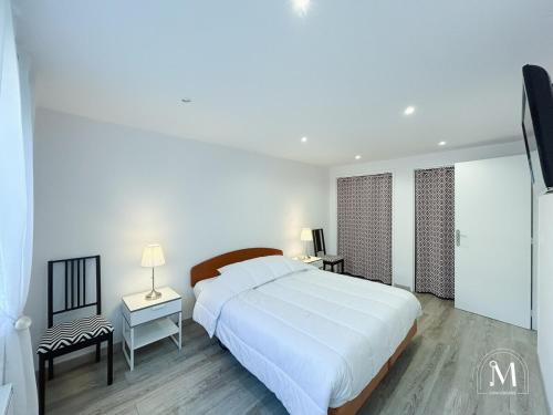 - une chambre blanche avec un grand lit blanc et une chaise dans l'établissement Charmant T3 en rez-de-jardin à Six-Fours, à Six-Fours-les-Plages