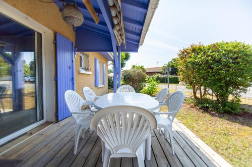 une table et des chaises blanches sur une terrasse dans l'établissement MAISON CRI-CRI à Arès, à Arès