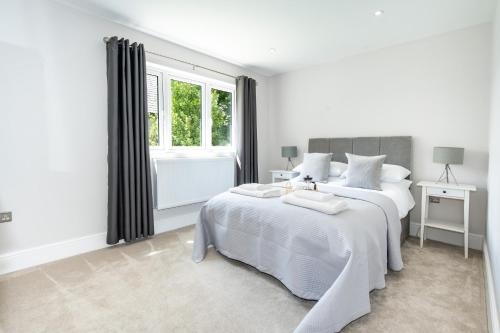 a white bedroom with two beds and a window at NEW! Stunning & Modern 5 bedroom home with Parking & Garden - Excellent Location! in Saint Leonards